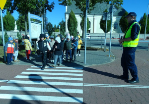 Policjant zapoznaje dzieci z podstawowymi zasadami bezpieczeństwa na drogach