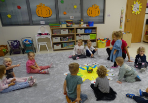 dziewczynka chodzi w kolo słoneczka i wrzuca koraliki