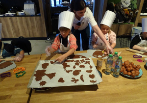 Dzieci układają gotowe ciasteczka na blaszki