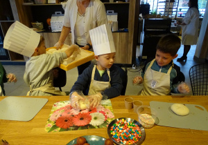 Dzieci biorą od pani surowe bułeczki