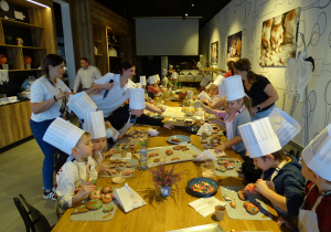 Dzieci dekorują pierniczki lukrem i posypką