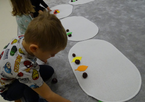 dzieci układają rytmy z kasztanów i liści