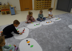 dzieci układają rytmy z kasztanów i liści