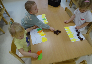dzieci układają rytmy z kasztanów i liści