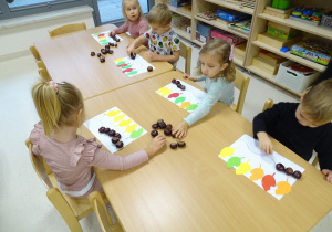 dzieci układają rytmy z kasztanów i liści