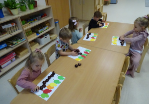 dzieci układają rytmy z kasztanów i liści