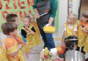 Nauczyciel pokazuje dzieciom składniki, z których będzie pieczone ciasto