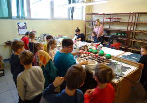 Dzieci oglądają ręczny proces ozdabiania szklanych bombek