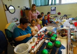 Dzieci oglądają ręczny proces ozdabiania szklanych bombek