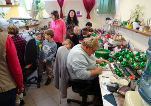 Dzieci oglądają ręczny proces ozdabiania szklanych bombek