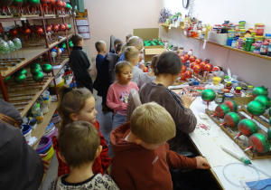 Dzieci oglądają ręczny proces ozdabiania szklanych bombek