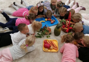dzieci wąchaja zgromadzone jarzyny i owoce