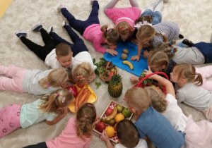 dzieci wąchaja zgromadzone jarzyny i owoce