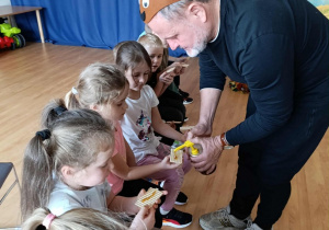 Pan częstuje dzieci wafelkiem z miodem