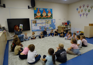 Dzieci siedzą w kole, pani pokazuje im obrazek z Polinką