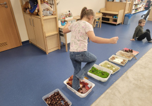 Dzieci idą boso po ścieżce sensorycznej ułożonej z darów jesieni