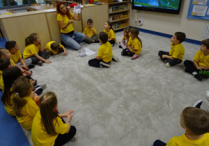 Pani pokazuje dzieciom karteczki z dobrym słowem i z zadaniami