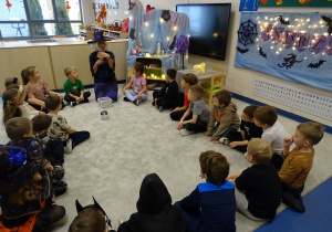 Dzieci siedzą na dywanie, słuchają czarodziejki