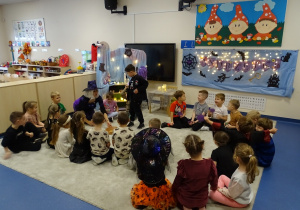 Dzieci pokazują kolorowe kółeczka, czarodziejka tłumaczy znaczenie koloru