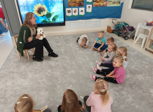 Logopeda z białym misiem pokazuje ćwiczenia języka