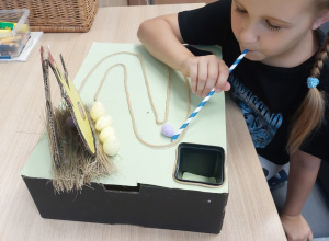 Dziewczynka wykonuje ćwiczenie oddechowe ze słomką