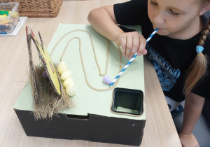 Dziewczynka wykonuje ćwiczenie oddechowe ze słomką