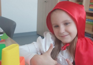 Dziewczynka jako Czerwony Kapturek ustawiła kolorową wieżę