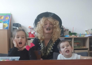 Chłopiec z dziewczynka naśladują ćwiczenia za logopedą