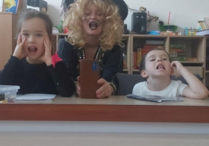 Dziewczynka, logopeda i chłopiec pokazują język ułożony na dziąsłach