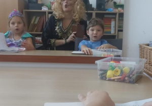 Dziewczynka, logopeda w stroju czarownicy i chłopiec wykonują ćwiczenia warg