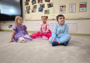 Dwie dziewczynki i chłopiec siedzą i chowają czerwień warg