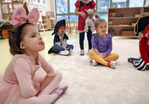 Dziewczynka na tle grupy zakrywa językiem wargę górną