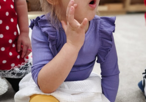 Dziewczynka dotyka policzka i tam układa język