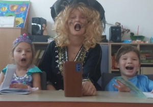 Dziewczynka, Pani w przebraniu Czarownicy i chłopiec, klaskają