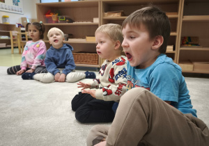 Chłopiec i inne dzieci układa język w kąciku ust.