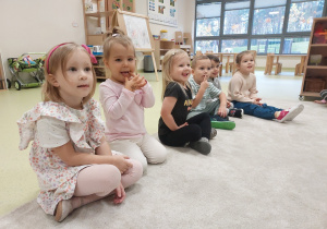 Dzieci siedzą w półkolu, wykonują zadania usprawniające język.