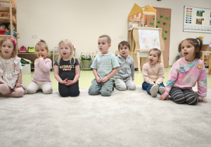 Dziewczynka i inne dzieci oblizują wargę dolną, malując na czerwony kolor.