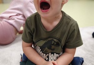 Chłopiec otwiera szeroko buzię.