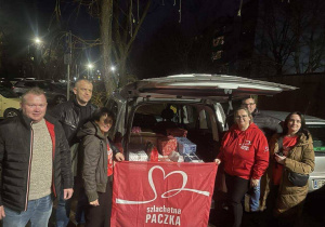 Panowie i koordynatorki stoją na tle napisu Szlachetna Paczka