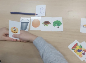 Dziecko pokazuje obrazek ciasto, na tle innych zakończonych na "O"