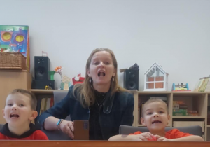 Chłopcy ćwiczą z logopedą język przed lustrem.