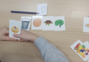 Dziewczynka pokazuje obrazek ciastko na tle innych kończących się samogłoską "O"