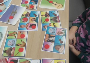 Logopedyczne Bingo na kartach ułożone czerwone kółka na oznaczenie usłyszanego dźwięku