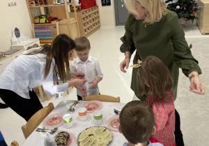 Panie wspólnie z dziećmi dzielą się opłatkiem.