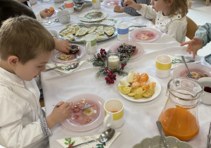 Dzieci jedzą wigilijne potrawy.