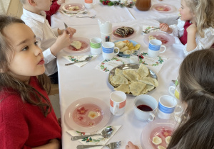 Dzieci jedzą wigilijne potrawy.