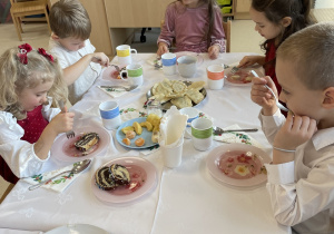 Dzieci jedzą wigilijne potrawy.