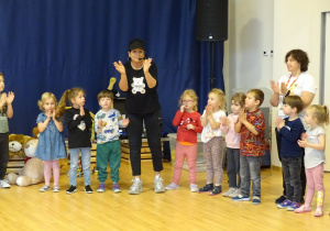 Pani prowadząca pokazuje ruchy do piosenki.