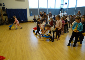 Dzieci wożą misie na taczkach.