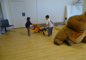 Dzieci wożą misie na taczkach.